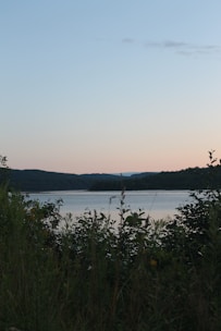 Sunset view over a serene lake with a cozy lakeside retreat surrounded by gentle hills.