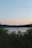 A serene lakeside view at sunset in Burundi, with gentle waves and lush greenery.