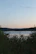 A serene lakeside view at sunset in Burundi, with gentle waves and lush greenery.