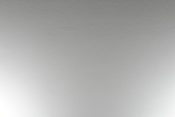 A close-up view of a plain, textured ceiling with a subtle off-white color.
