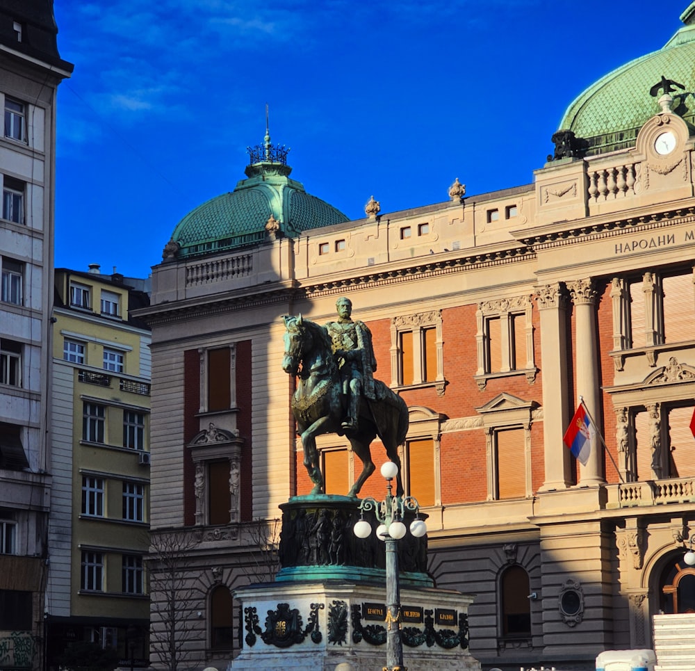 eine Statue eines Mannes, der vor einem Gebäude auf einem Pferd reitet