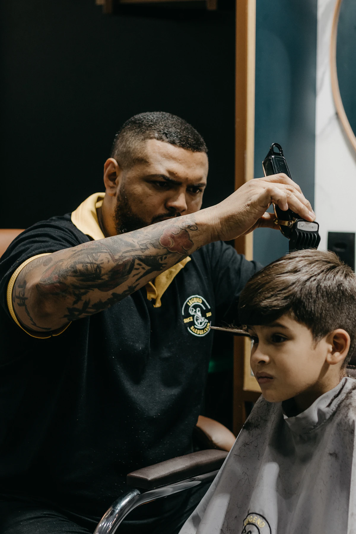 Barber trimming a young boy's hair in the chair at Guillen Dominican Barber Shop