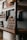 Wooden shelves display rows of small jars and various bottles. The jars are stacked in a pyramid shape, each labeled, suggesting they contain products like creams or condiments. The rustic wooden design paired with the neatly arranged items creates an organized and artisanal appearance.