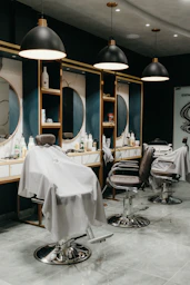a hair salon with chairs and mirrors and lights