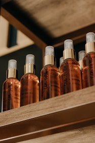 Bottles of golden cold-pressed oils lined up on a wooden shelf with soft natural light.