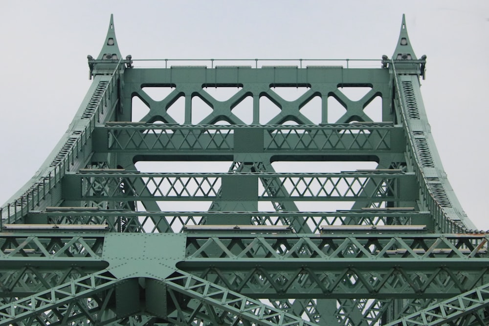 a large green bridge with a clock on it's side