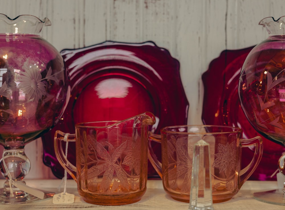 a table topped with pink glass dishes and vases