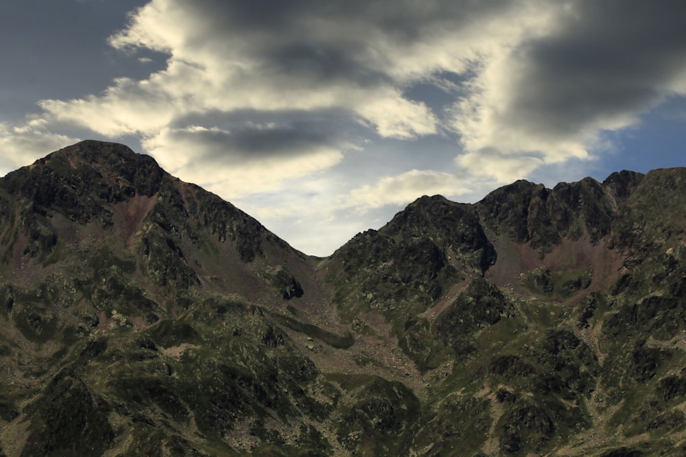 a group of mountains with a cloudy sky in the background