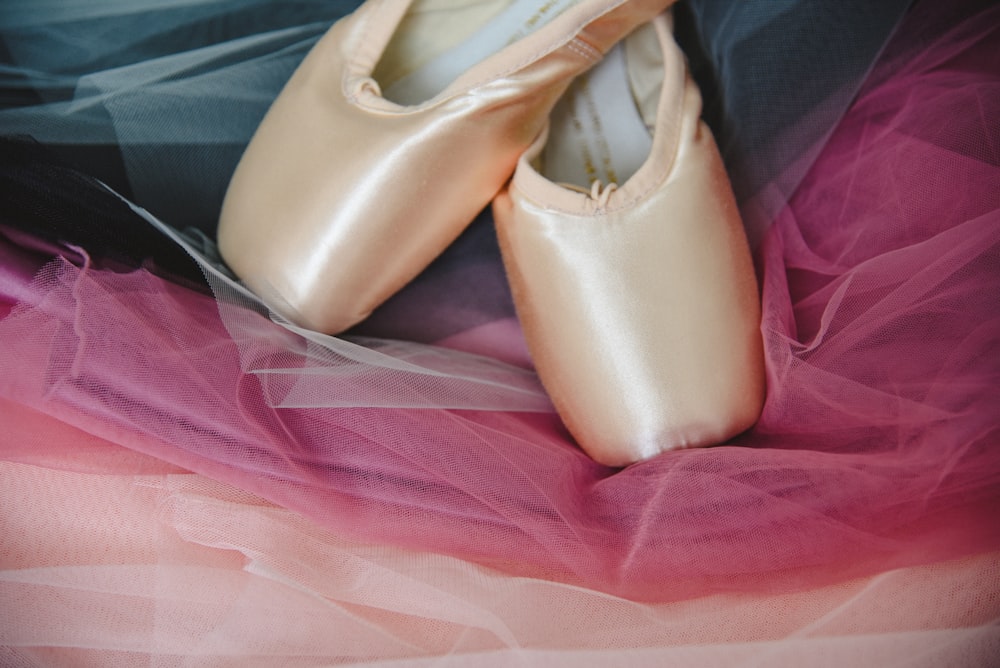 a pair of ballet shoes sitting on top of a bed