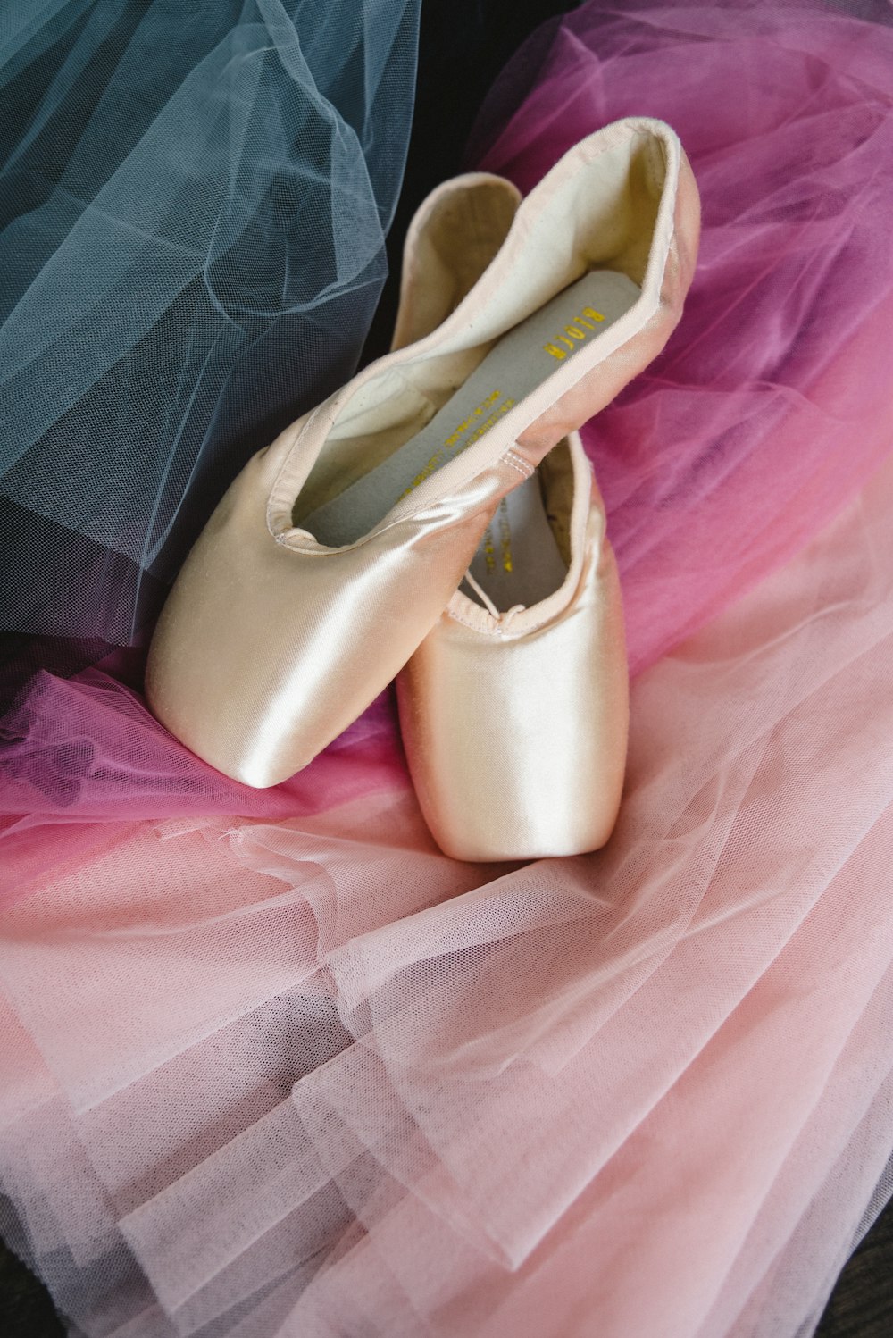 a pair of ballet shoes sitting on top of a pink tulle skirt