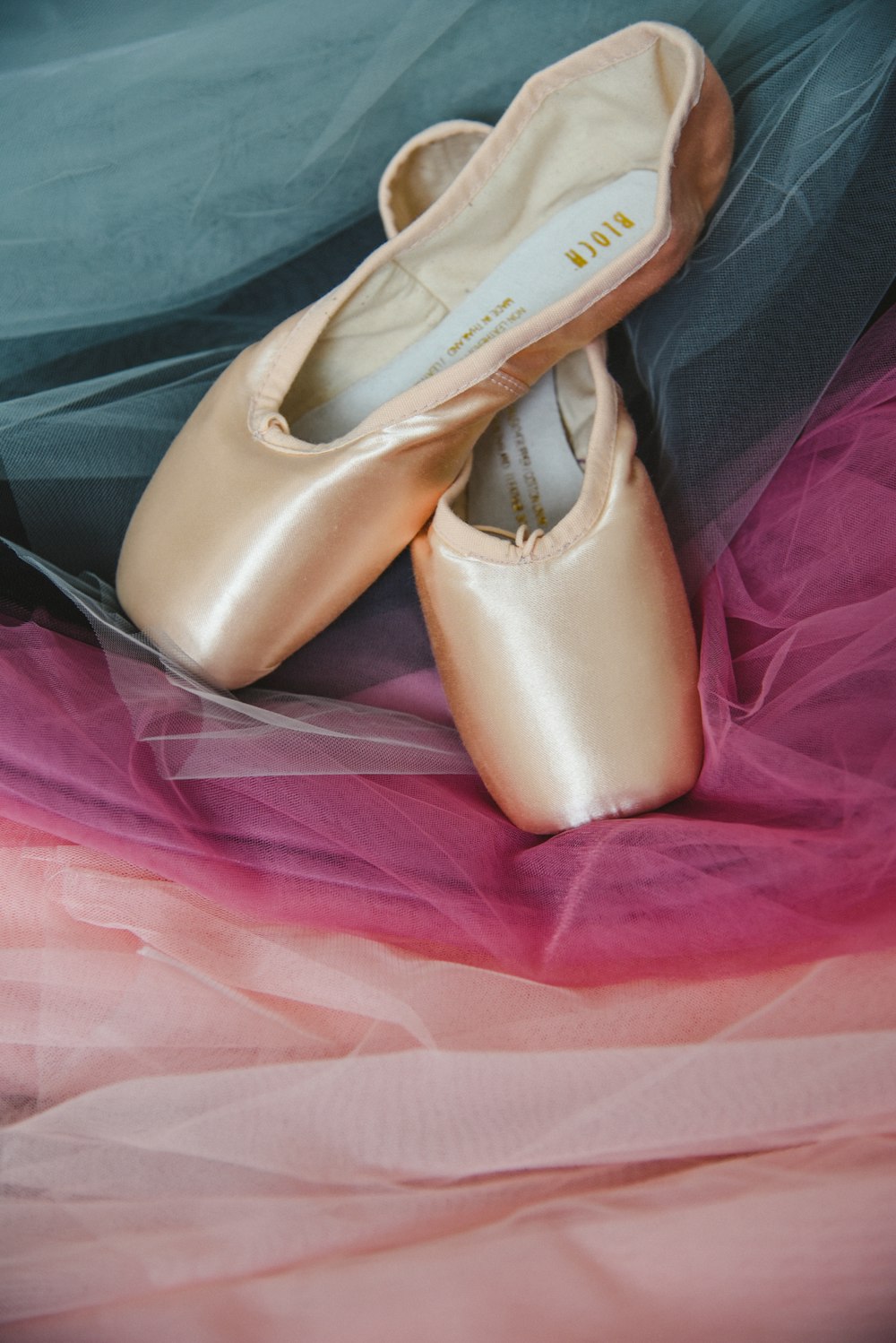 a pair of ballet shoes sitting on top of a bed