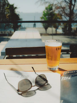 Couple enjoying a sunny afternoon with craft beer in a rustic setting.