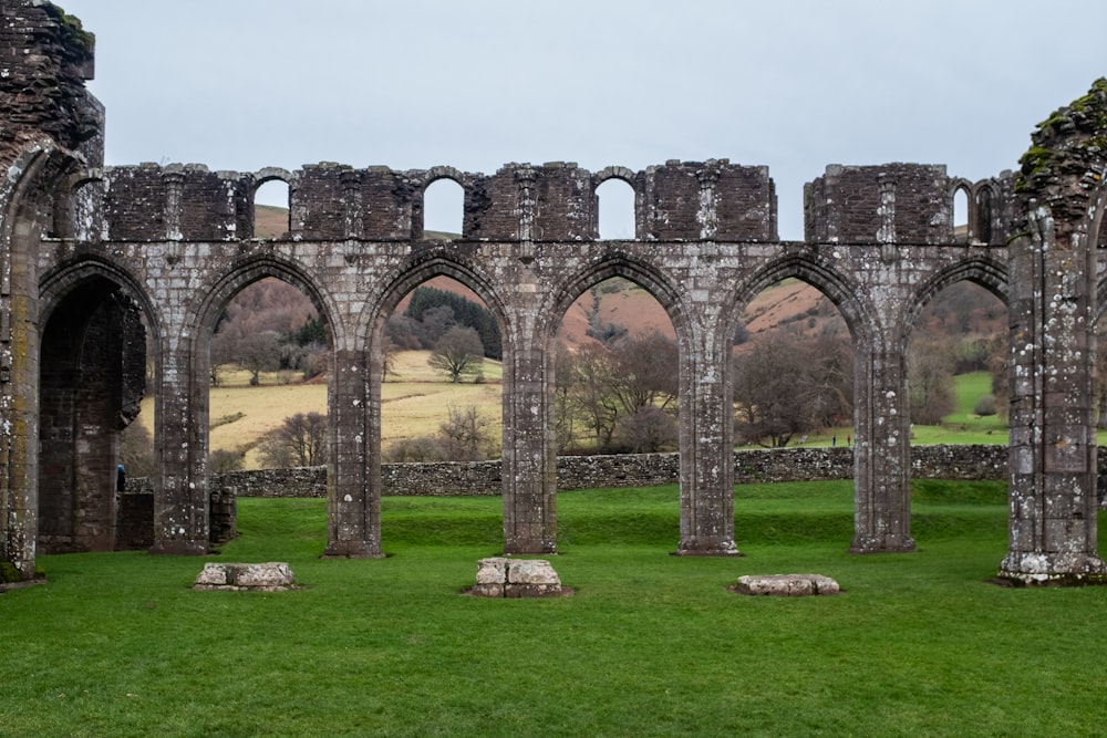 a stone building with arches and grass in front of it