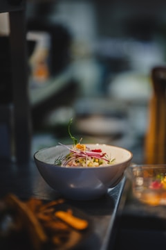 A vibrant ceramic mixing bowl filled with colorful salad ingredients on a rustic kitchen counter.
