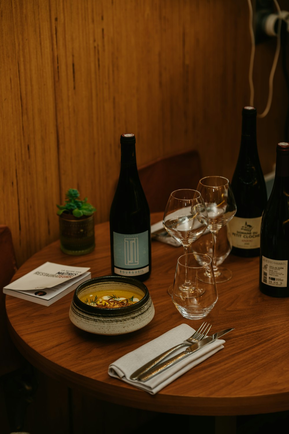 a wooden table topped with glasses and bottles of wine