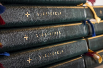 A stack of dark green leather-bound books with gold lettering and crosses embossed on the spine. Each book has several colorful ribbon bookmarks hanging from the top.
