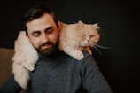a man holding a cat on his shoulders