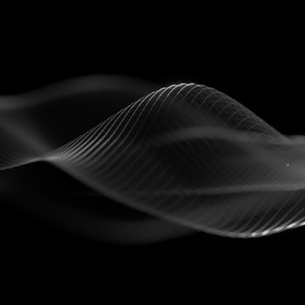 Flowing, translucent waves of light create a dynamic and ethereal pattern against a black background. The fluid lines appear to form abstract, wave-like shapes, giving a sense of movement and delicacy.