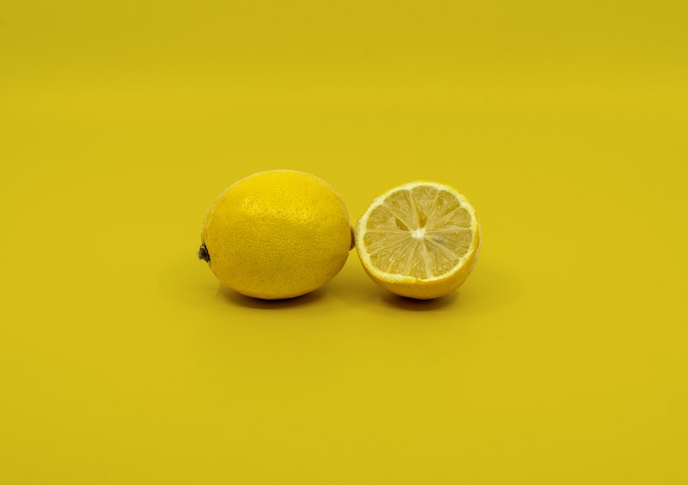 a half and a whole lemon on a yellow background