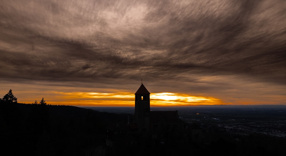 a clock tower on top of a hill under a cloudy sky