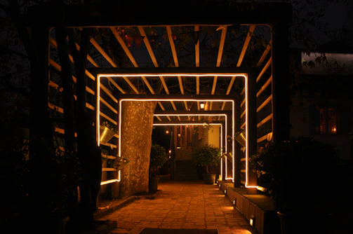 Outdoor garden pathway illuminated by subtle ground lights and soft overhead fixtures.