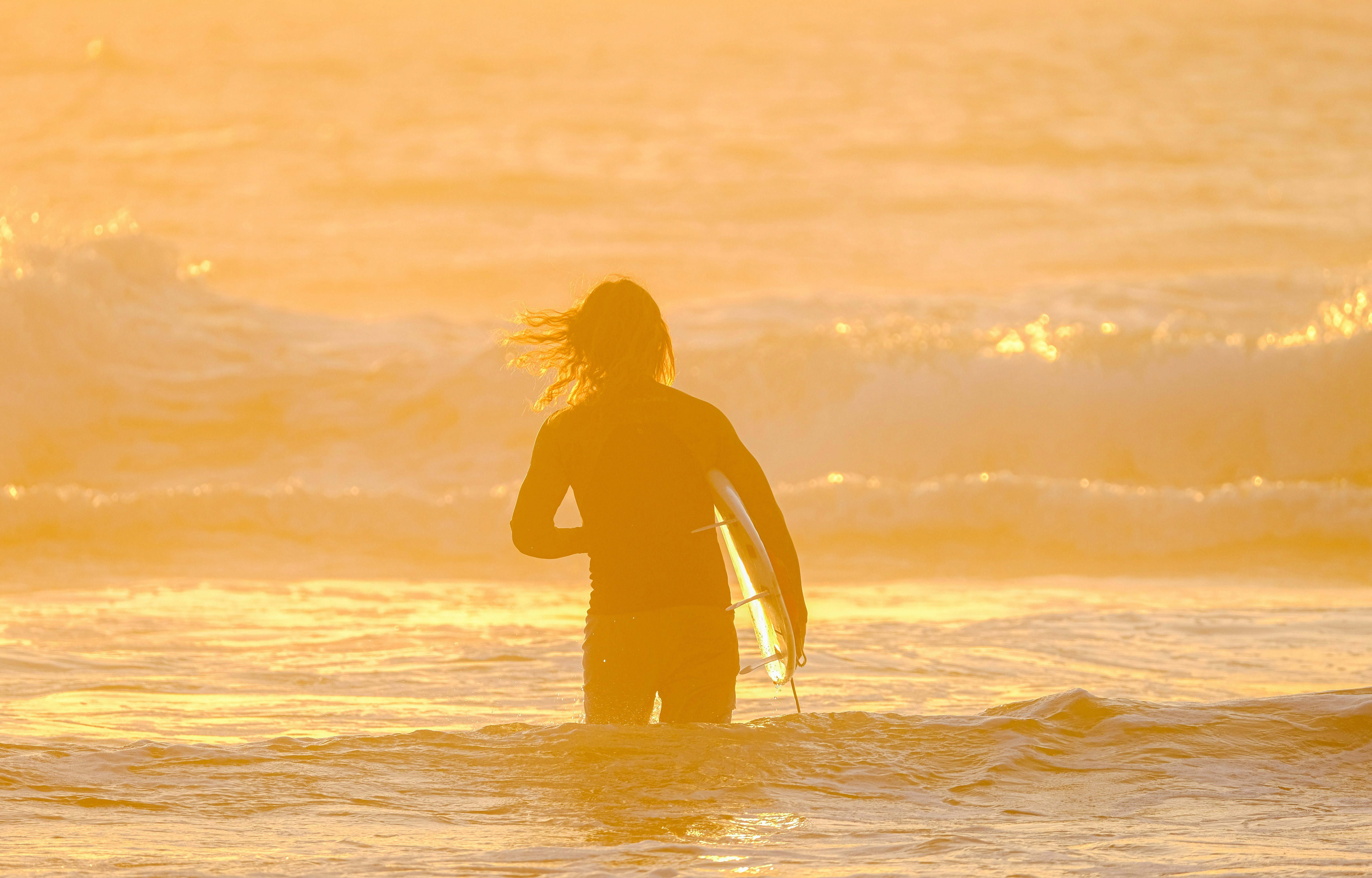 a person standing in the water with a surfboard, 