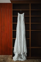 Close-up of a detailed lace dress on a hanger against a neutral background