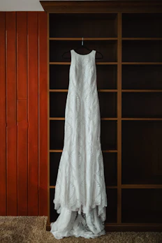 An elegant dress with delicate lace details hanging on a vintage brass rack in a cozy room.
