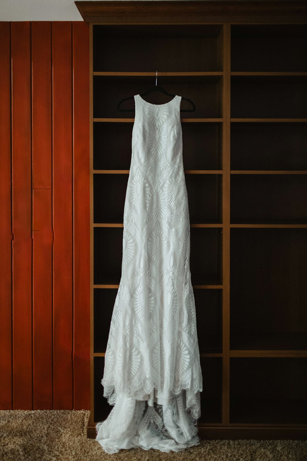 a wedding dress hanging in front of a bookcase
