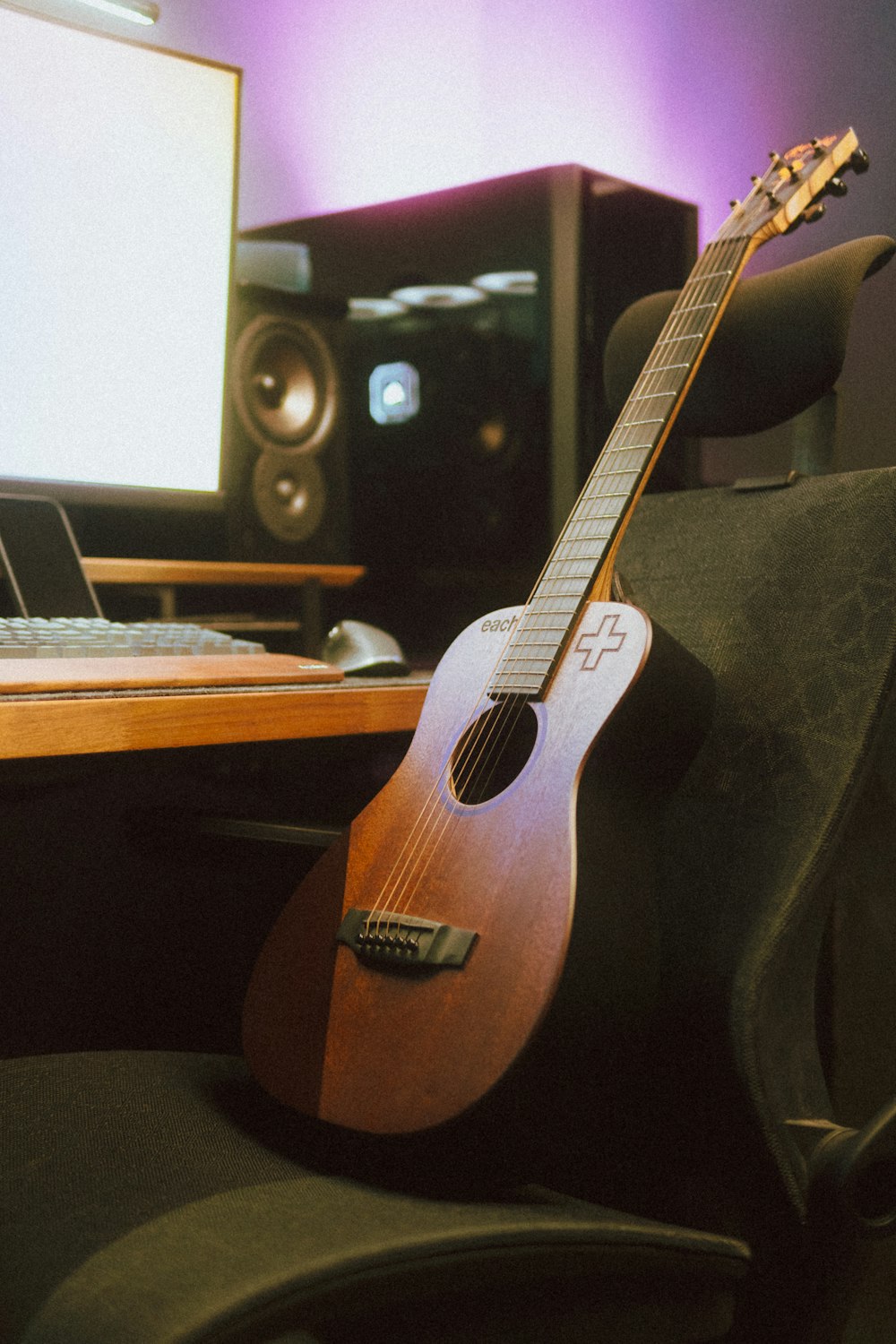 a guitar sitting on a chair in front of a computer