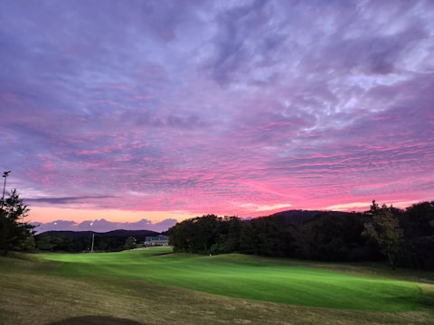 A scenic golf course at sunrise with vibrant traditional brand colors in the sky.
