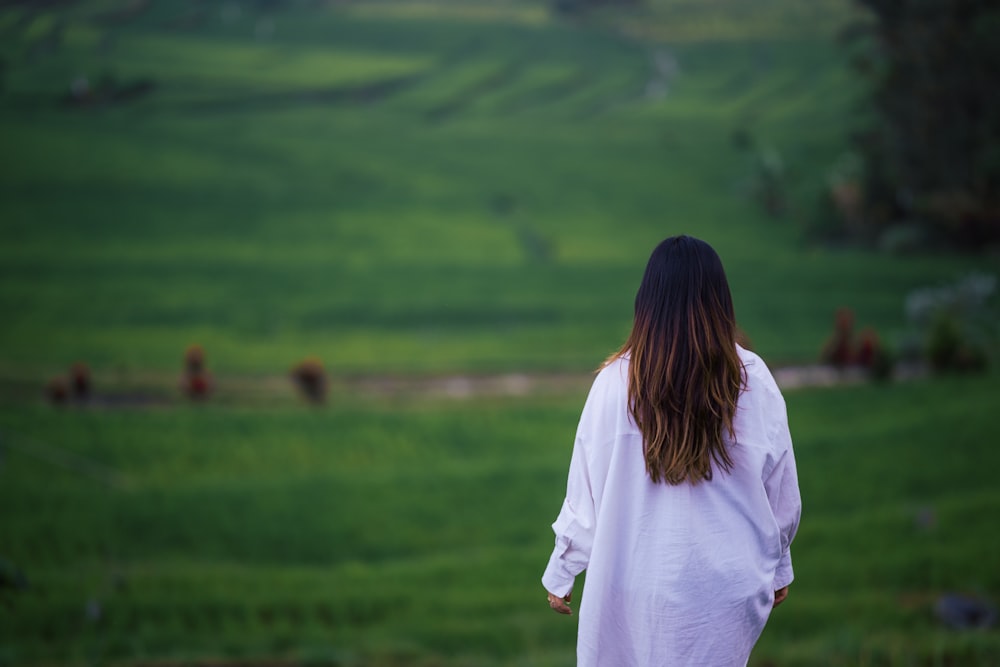 a woman standing in front of a lush green field