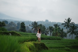 a woman in a white dress standing in a green field