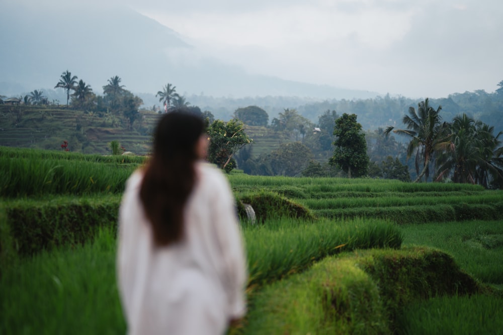 a woman walking through a lush green field