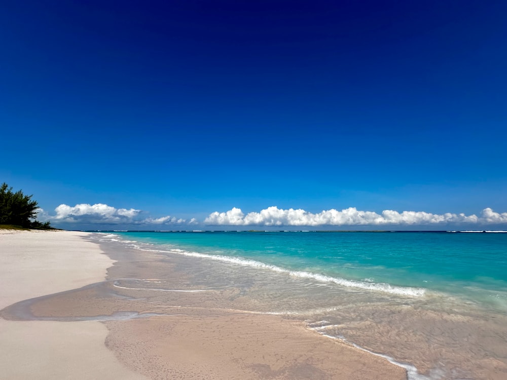 a sandy beach with clear blue water and white sand