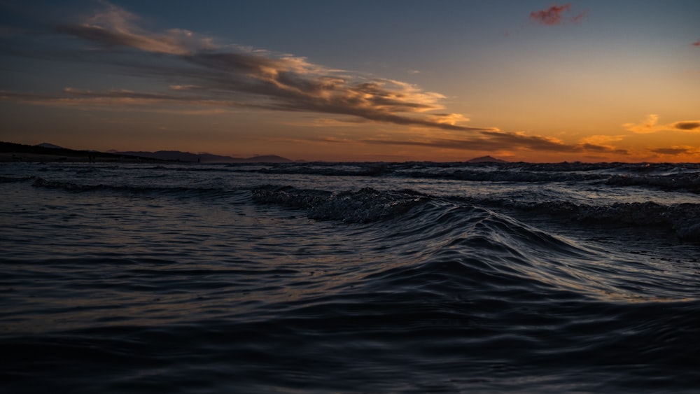 the sun is setting over the ocean waves