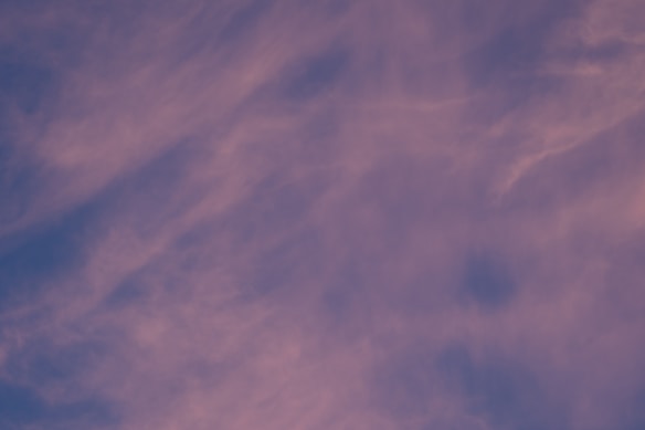 The image features a sky filled with soft, wispy clouds in shades of purple and blue, creating a calm and soothing atmosphere. The clouds appear to be gently moving across the sky, blending seamlessly into each other.