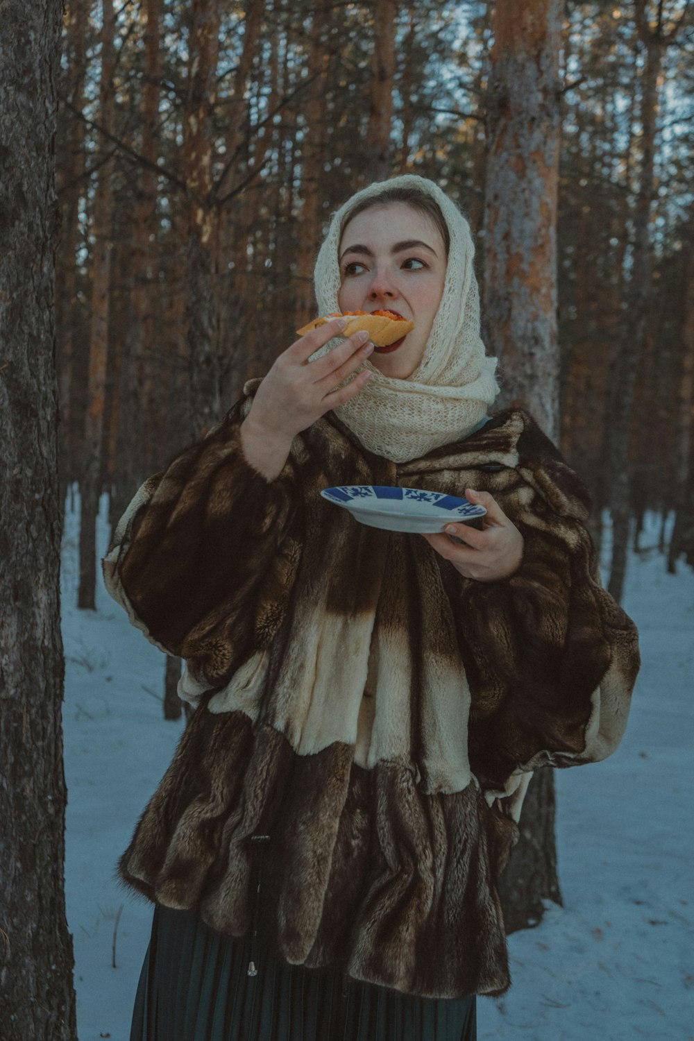 una mujer con un abrigo de piel comiendo un pedazo de comida