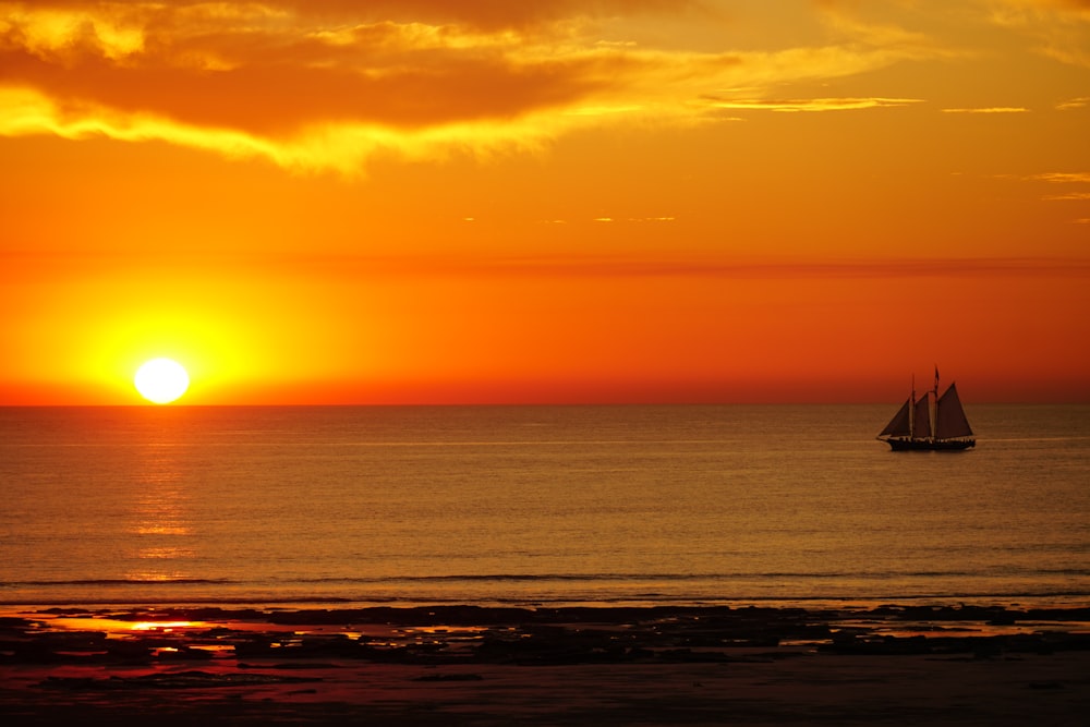 a sailboat in the ocean at sunset