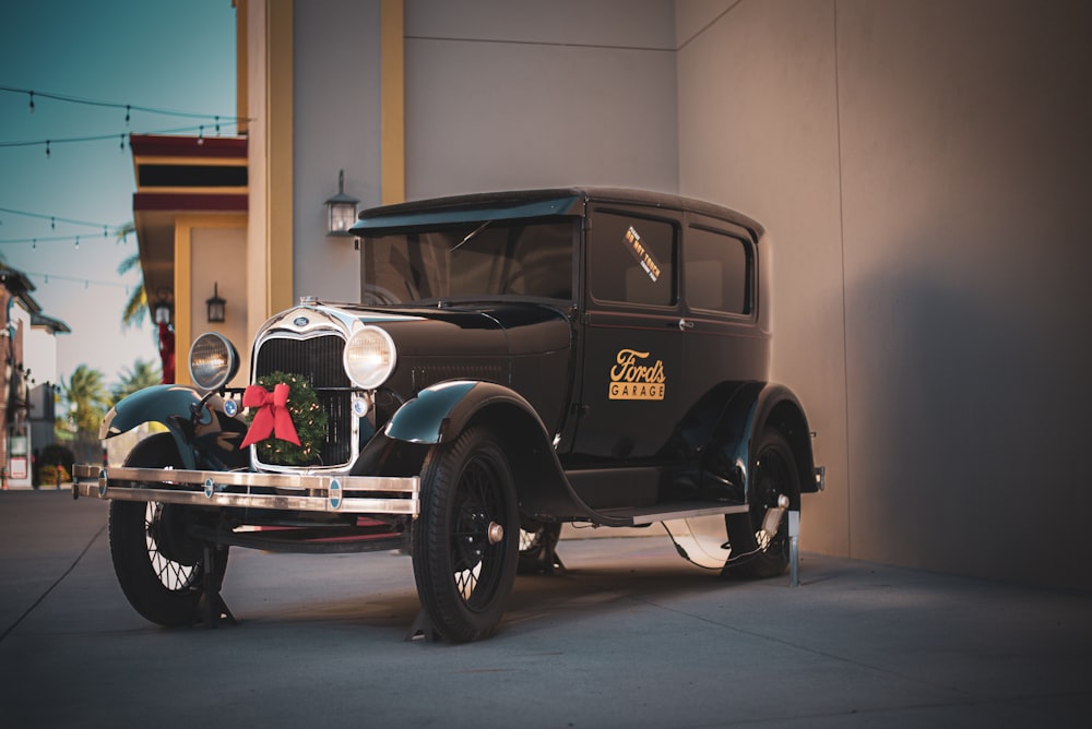 an old model car is parked in front of a building