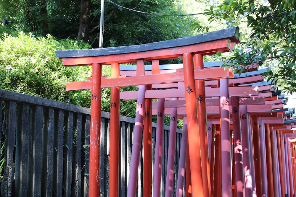 a row of red wooden chairs sitting next to a fence