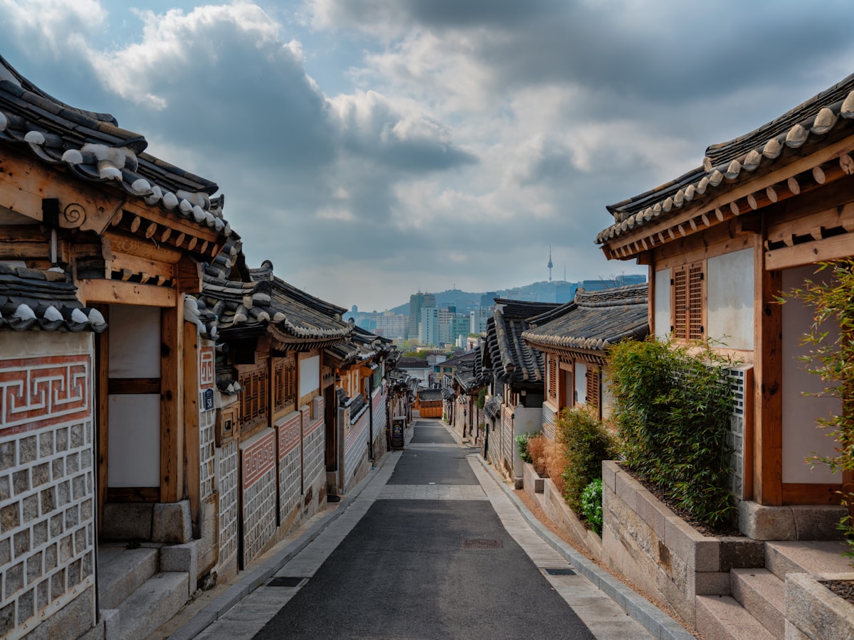A street in Seoul lined with low wooden buildings under a cloudy sky