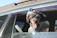 A happy dog peeking out of a sleek, modern pet carrier backpack on a sunny day.