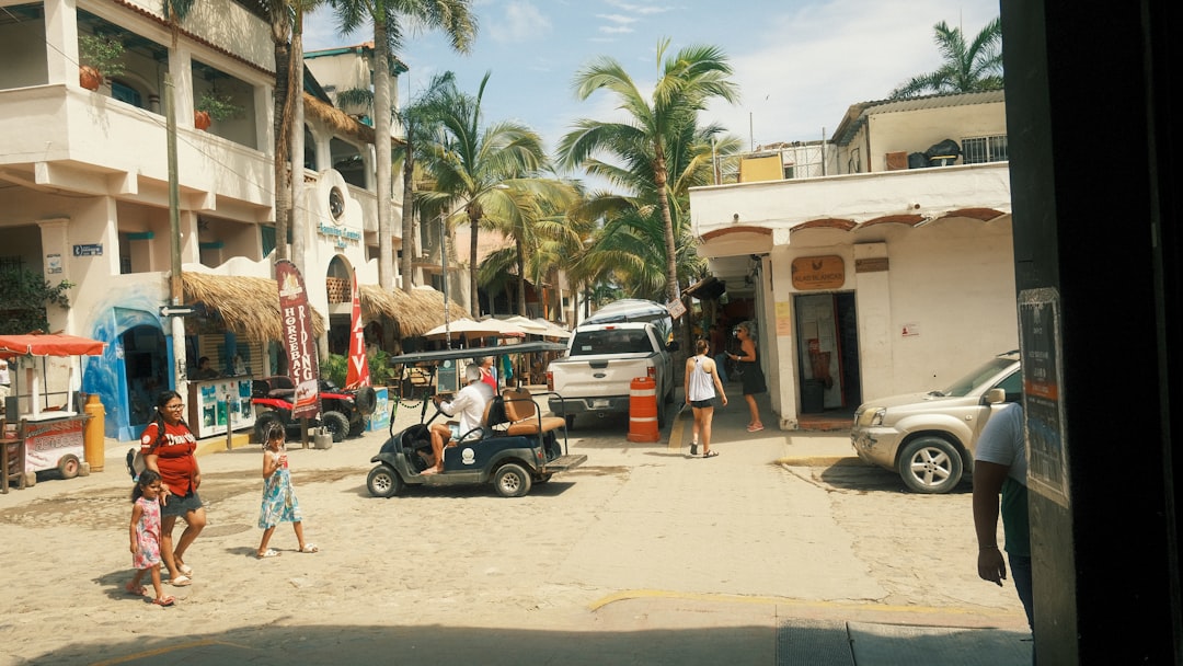a group of people walking down a street next to parked cars,