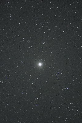 A night sky filled with countless stars. In the center, there is a brighter celestial object, possibly a galaxy or nebula, standing out against the dark backdrop. The vast, deep space evokes a sense of wonder and mystery.