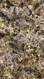 Modern artificial Christmas tree with white branches and warm glowing lights