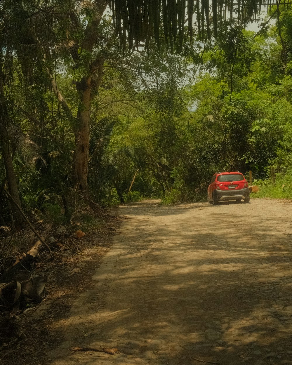 a red car driving down a dirt road