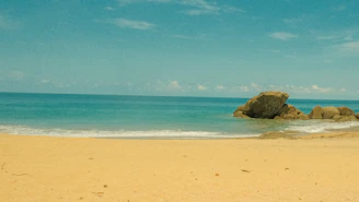 A serene beach scene with golden sands and turquoise waves under a clear sky.