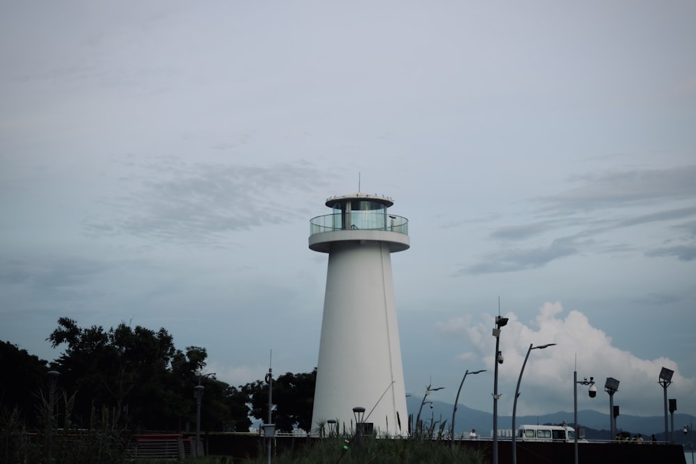 a white light house sitting on top of a lush green field