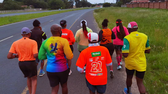 A group of diverse people jogging together on a sunny trail, smiling and encouraging each other.